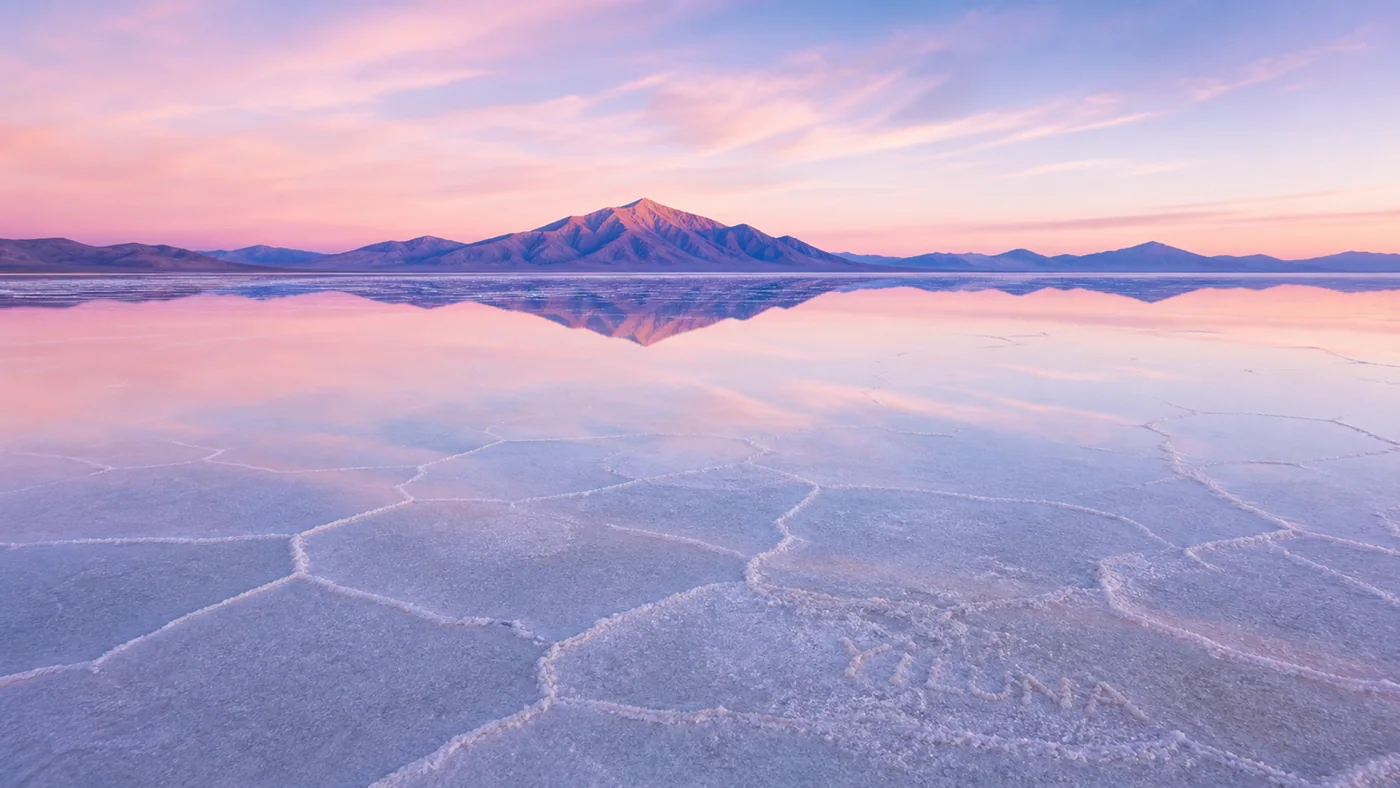 Rose Salt Mirror — A dawn salt mirror reduces nature to rose sky, blue reflection, mineral white, and lavender distance.